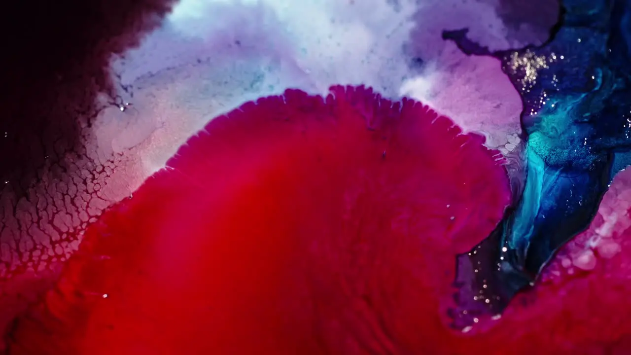 Vibrant ink clouds diffusing in water creating an abstract mix of red blue and purple hues