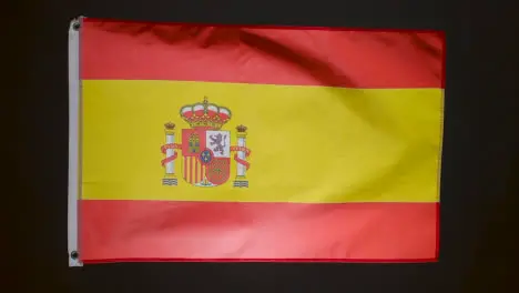 Studio Shot Of Flag Of Spain Flying Against Black Background