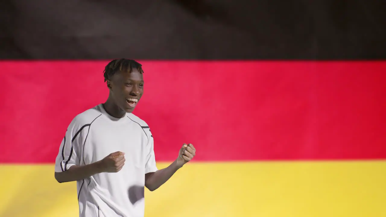 Young Footballer Celebrating to Camera In Front of Germany Flag 