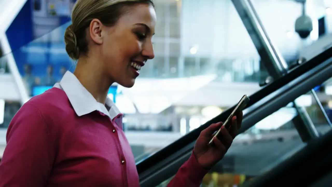 Woman on escalator texting on mobile phone 