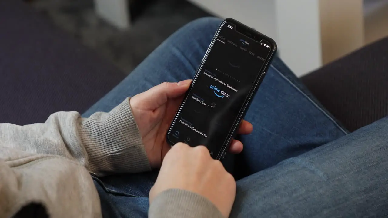 Young woman using Amazon Prime Video app on an iPhone in casual home environment