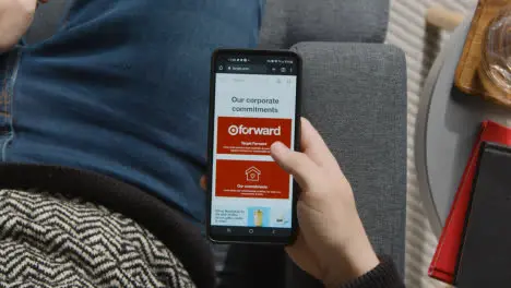 Overhead Shot Of Person At Home Shopping Online Looking At Target Website On Mobile Phone