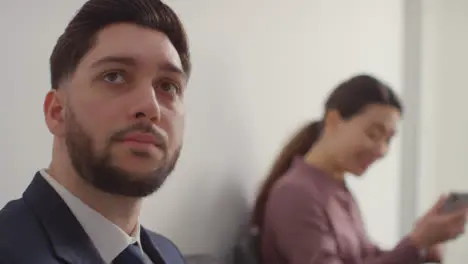 Male And Female Candidates In Office Waiting For Job Interview Looking At Mobile Phone And Reading Notes 6