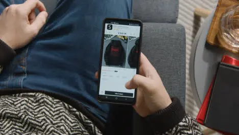 Overhead Shot Of Person At Home Shopping Online Looking At Shein Website On Mobile Phone