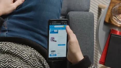 Overhead Shot Of Person At Home Shopping Online Looking At Walmart Website On Mobile Phone 2