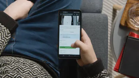 Overhead Shot Of Person At Home Shopping Online Looking At Asos Website On Mobile Phone 2