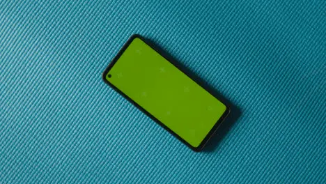 Overhead Studio Fitness Shot Of Rotating Green Screen Mobile Phone On Blue Exercise Mat