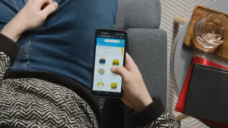 Overhead Shot Of Person At Home Shopping Online Looking At Walmart Website On Mobile Phone