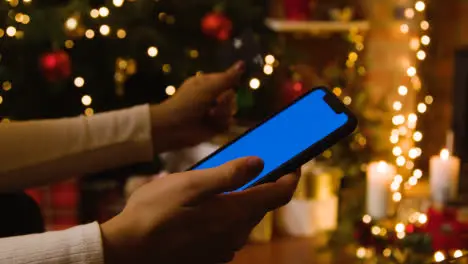 Christmas At Home With Person Making Card Purchase On Blue Screen Mobile Phone