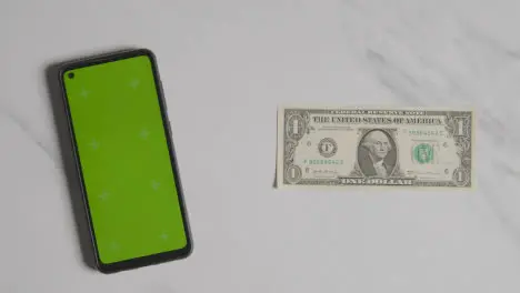 Overhead Currency Shot Of US 1 Dollar Bill Next To Green Screen Mobile Phone