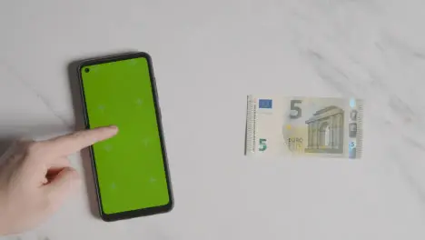 Overhead Currency Shot Of 5 Euro Note Next To Person Using Green Screen Mobile Phone