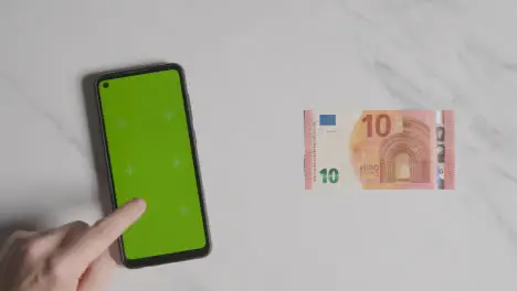 Overhead Currency Shot Of 10 Euro Note Next To Person Using Green Screen Mobile Phone