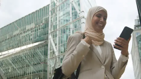 Muslim Businesswoman Celebrating Good News On Mobile Phone Standing Outside Office In City