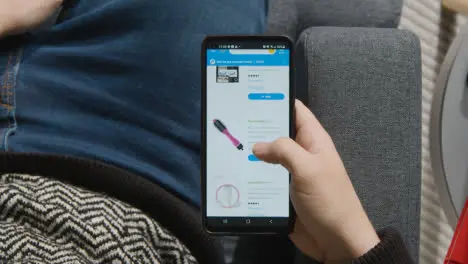 Overhead Shot Of Person At Home Shopping Online Looking At Walmart Website On Mobile Phone 1