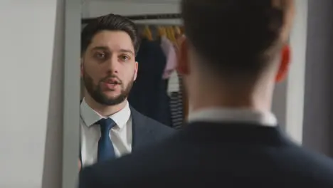 Young Man In Suit At Home Practising Job Interview Technique Reflected In Mirror Using Mobile Phone 2