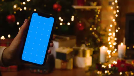 Christmas At Home With Person Holding Blue Screen Mobile Phone