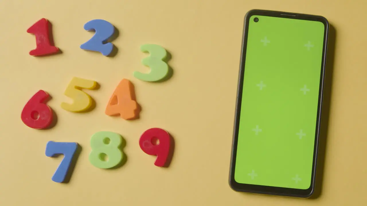 Studio Overhead Shot Of Plastic Numbers Arranged In Order With Green Screen Mobile Phone On Yellow Background 1