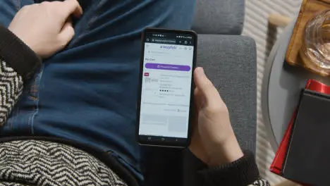 Overhead Shot Of Person At Home Shopping Online Looking At Wayfair Website On Mobile Phone