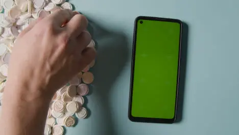 Person Choosing From Pile Of Heart Candy With Romantic Messages Of Love Next To Green Screen Mobile Phone