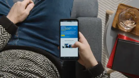 Overhead Shot Of Person At Home Shopping Online Looking At Bestbuy Website On Mobile Phone On Black Friday