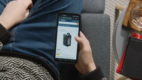 Overhead Shot Of Person At Home Shopping Online Looking At Amazon Website On Mobile Phone 1