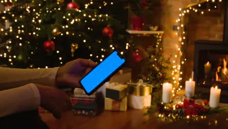 Christmas At Home With Person Looking At Blue Screen Mobile Phone 2