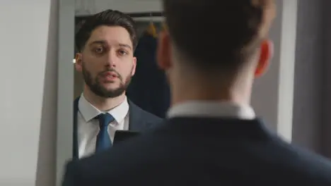 Young Man In Suit At Home Practising Job Interview Technique Reflected In Mirror Using Mobile Phone