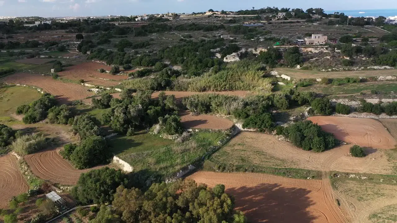 Drone shot tracking zooming away from Bidnija fields