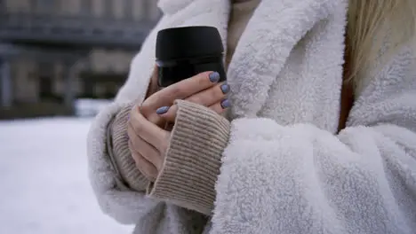 Blonde girl holding hot thermos