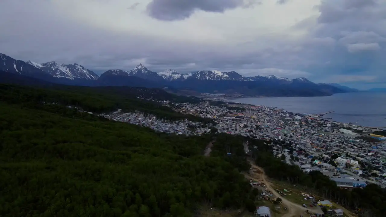 Drone shot flying over Ushuaia Argentina towards the Andes mountains in the distance on a cloudy day