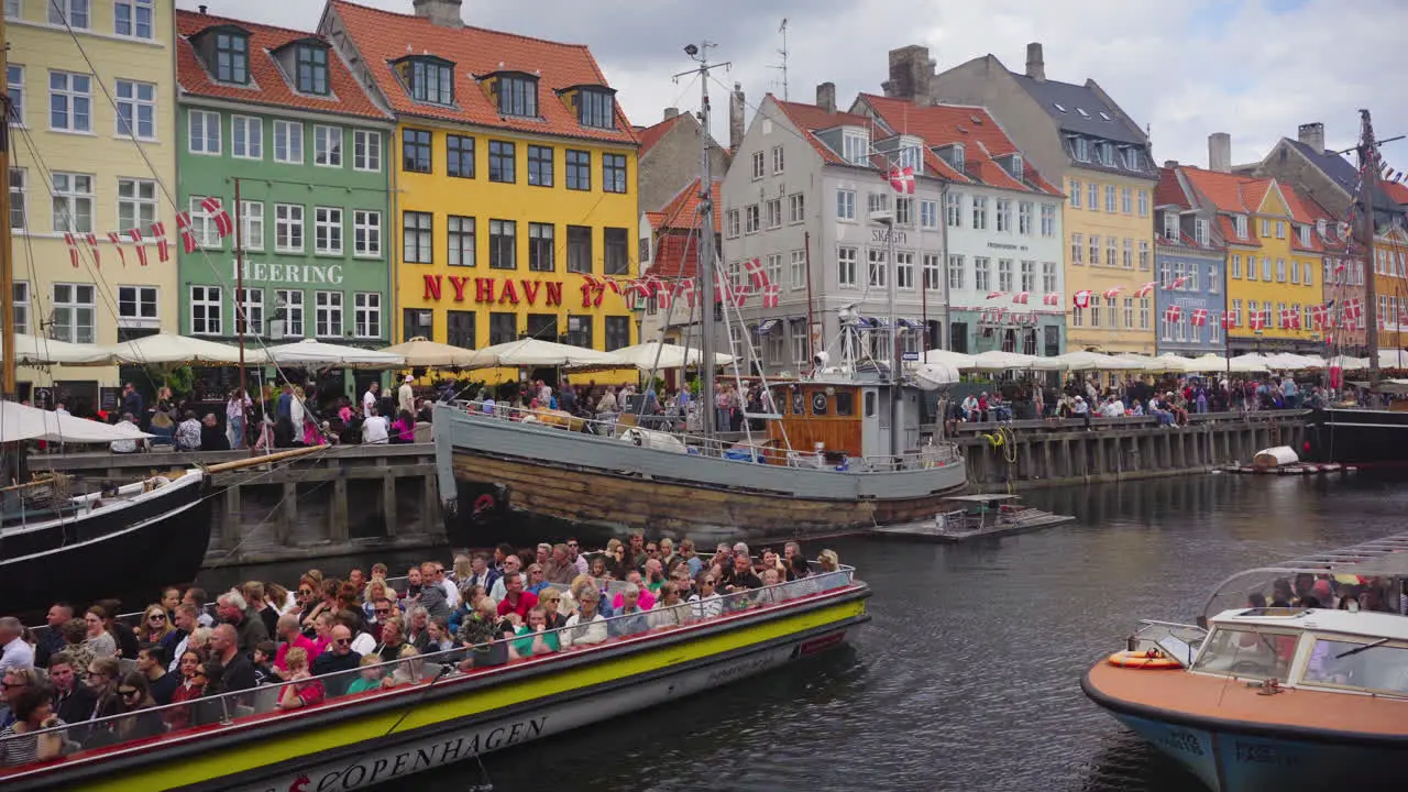 A peaceful look over Nyhavn as boat full of tourists maneuvers the canal