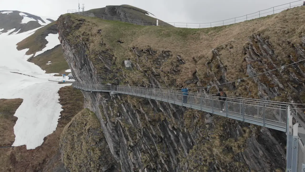 Pedestrian Suspension Bridge Over Cliff with Two People Walking in the Winter