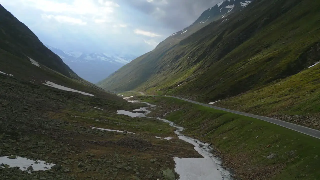 Cinematic drone shot of a single car through a mountain road in the alps