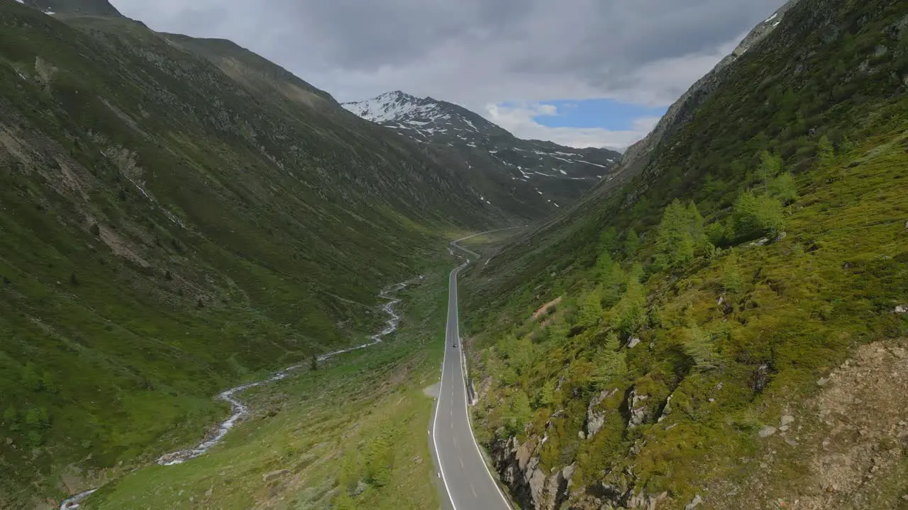 Epic cinematic drone shot of a single car through a mountain road in the alps