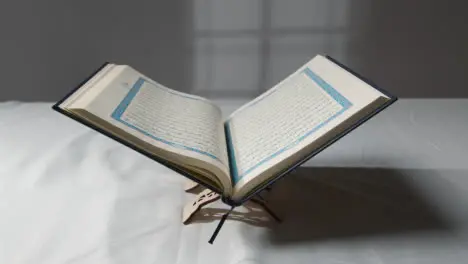 A Handheld Shot of the Quran On Covered Surface