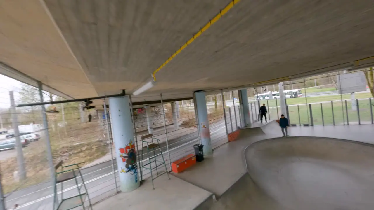 smooth fpv flight of a young skater skateboarding a bowl in a underground skatepark