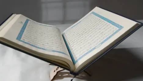 A Handheld Tracking Shot of the Quran On Covered Surface