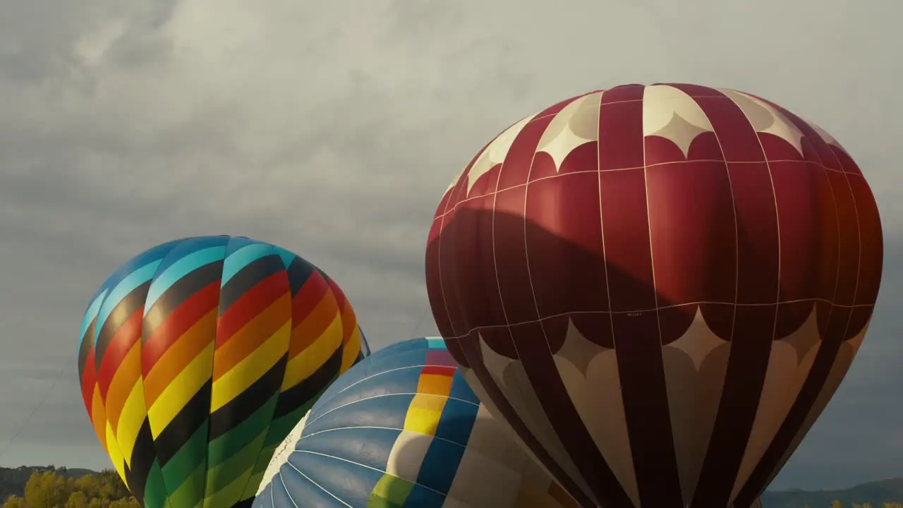 Colorful hot air balloons fully inflated and waiting to take off from the ground at sunrise or sunset with clouds in the background