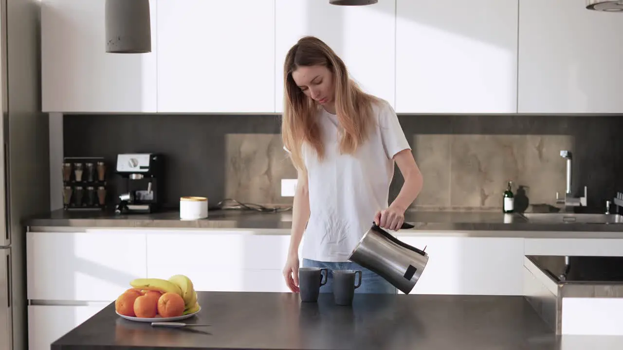 A Young Woman Pours Tea Into A Cups From A Kettle