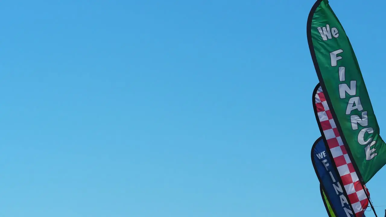 Colorful advertising pennants flapping in a strong breeze against clear blue sky