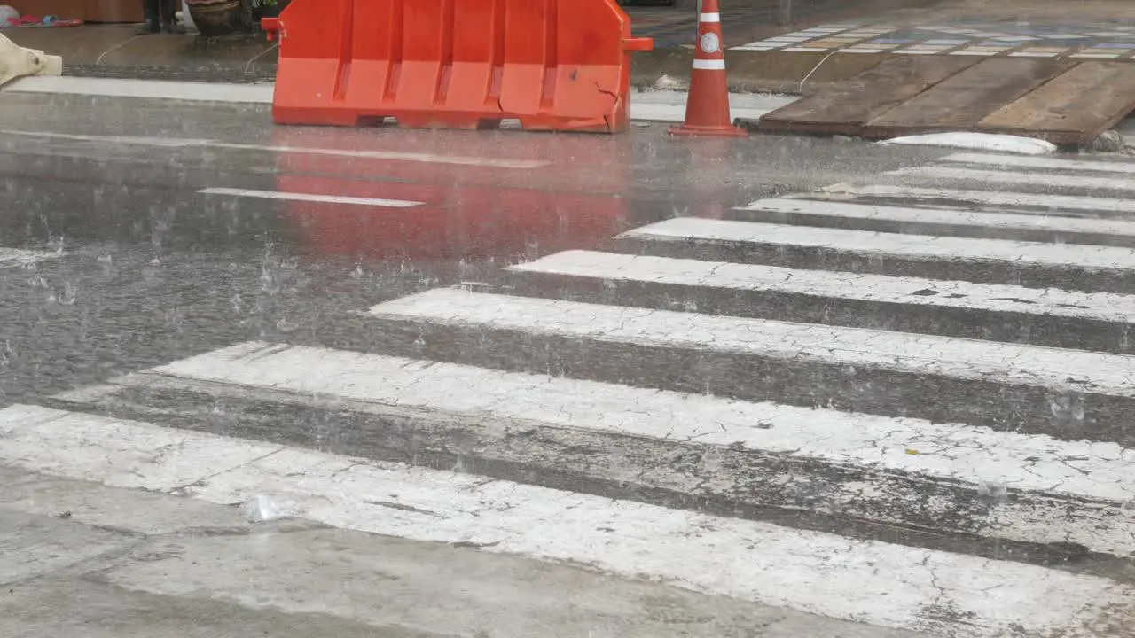 low angle view to the local street while heavy raining in rainy season with some cars driving water wet splash on the road street surface with thunderstorm natural background