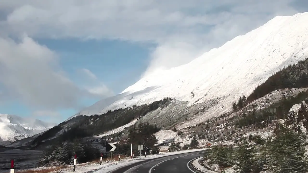 Road trip in the highlands of Scotland winter landscape snowy mountains at the background cloudy traveling shot