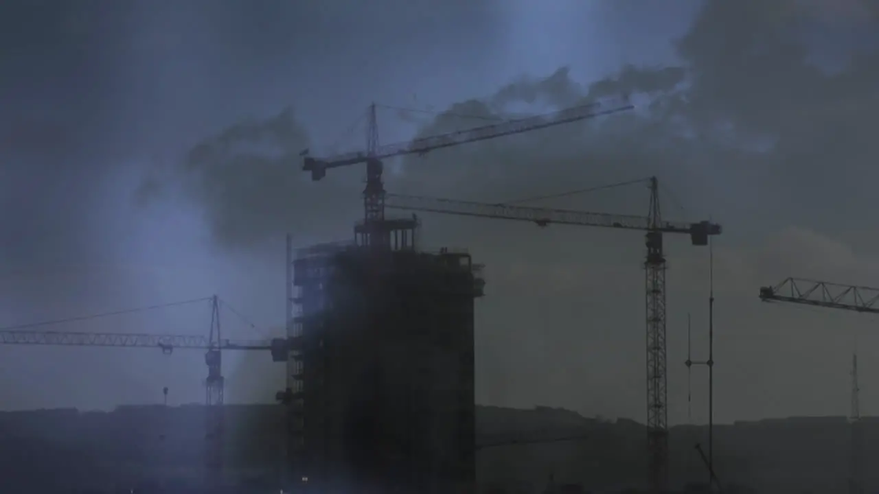 Cranes on top of a building and lightning