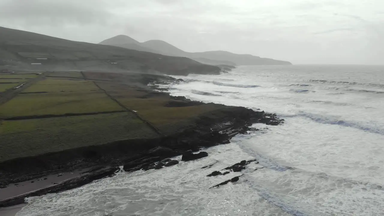 Aerial of atlantic seascape next to sandy beach waves and black rocks