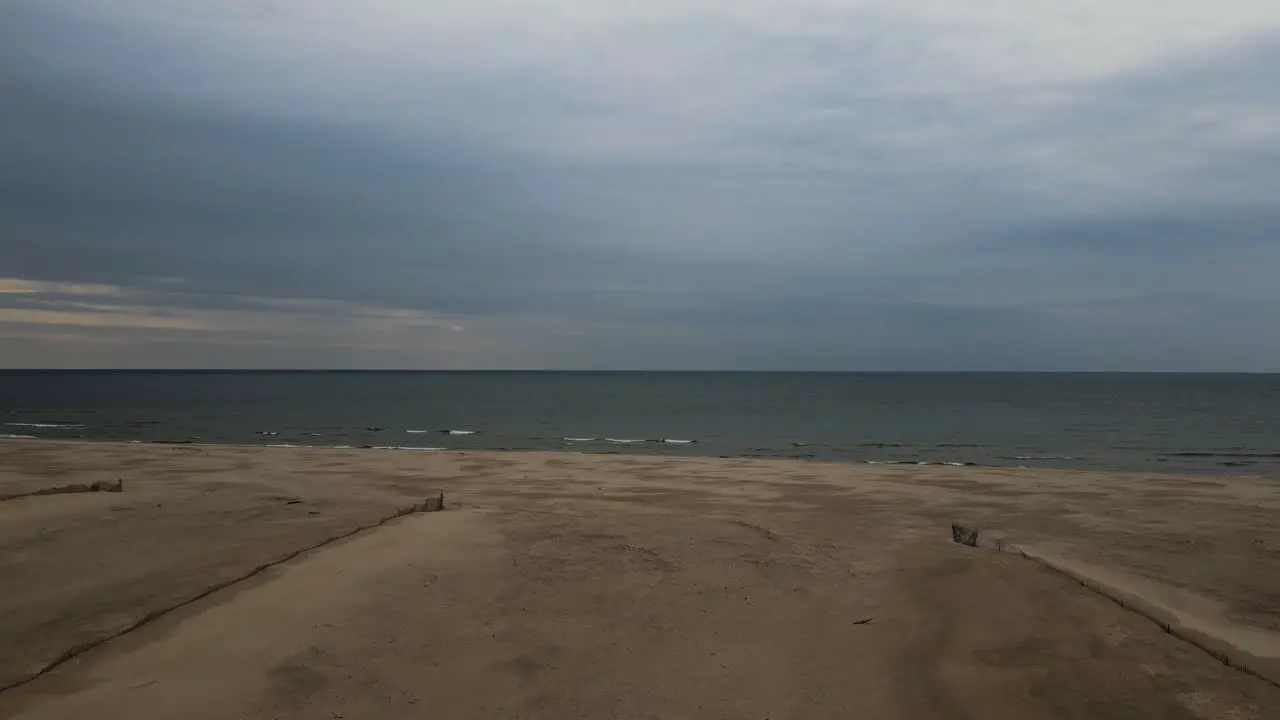 Drone dolly backward near whitecaps cresting on the shore