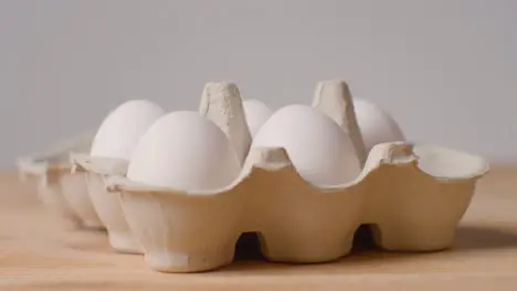 Studio Shot Of Person Opening And Choosing From Cardboard Boxes Containing White Eggs Against Grey Background 1