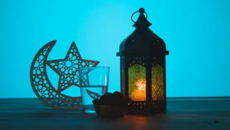 Tracking Shot of a Lantern Water and Dates On a Table During Dusk Ramadan Celebrations