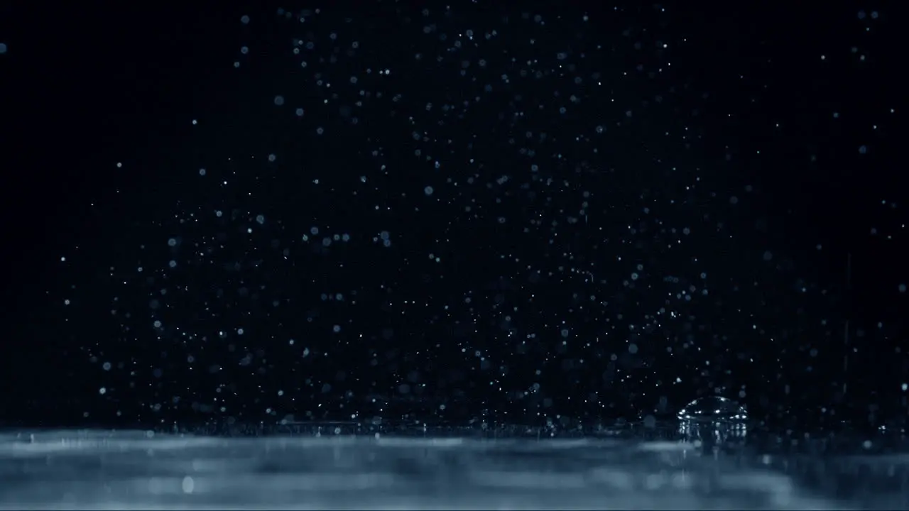 Monochromatic close up of water splashing over a calm surface on black background