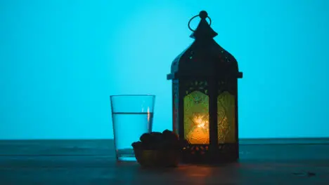 Tracking Shot of Lantern Water and Dates On a Table During Dusk Ramadan Celebrations