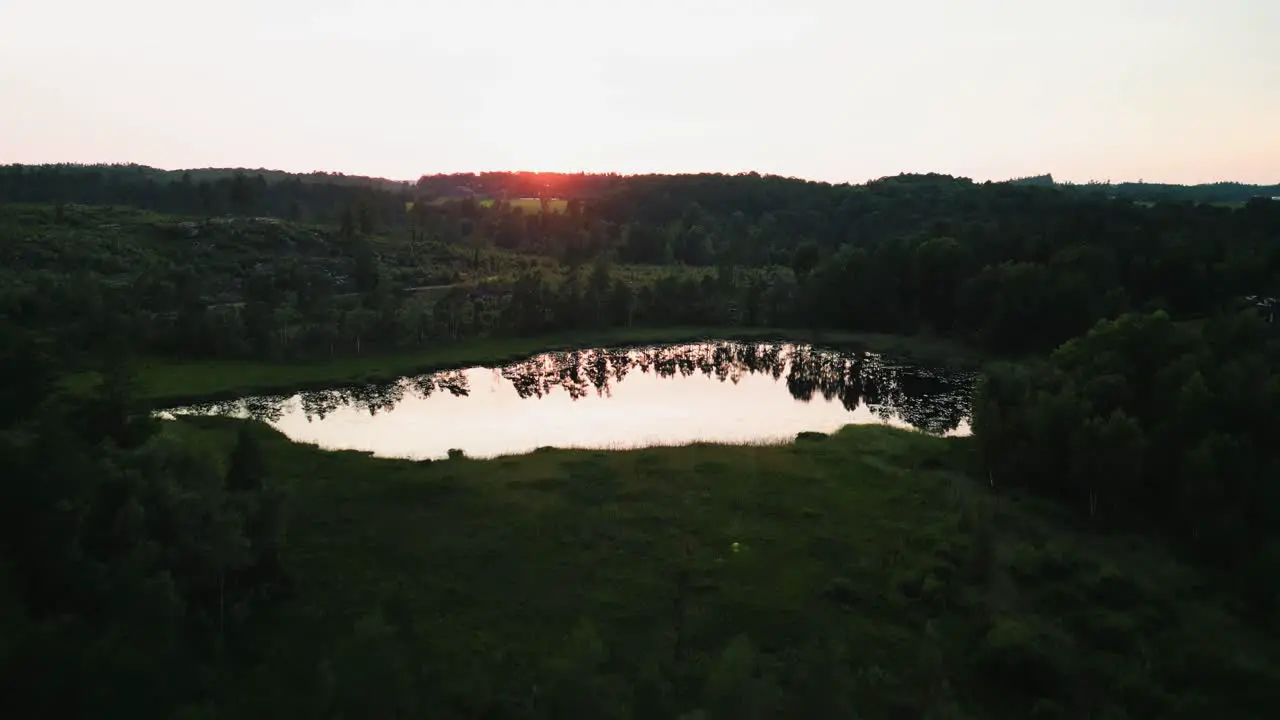 Aerial ascent of calm lake at sunset Hällingsjö Sweden